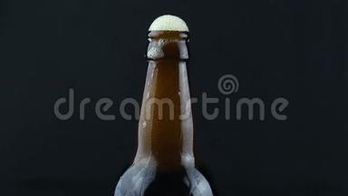 啤酒泡沫沿着一瓶雾蒙蒙的啤酒流下来。 啤酒泡沫顺着一瓶深色啤酒流下来..